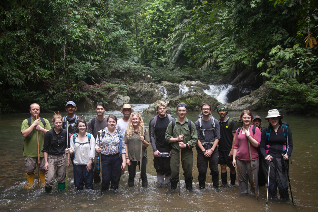 Students from the 2015 field trip pose in front of a waterfall inside the Tane' Olen